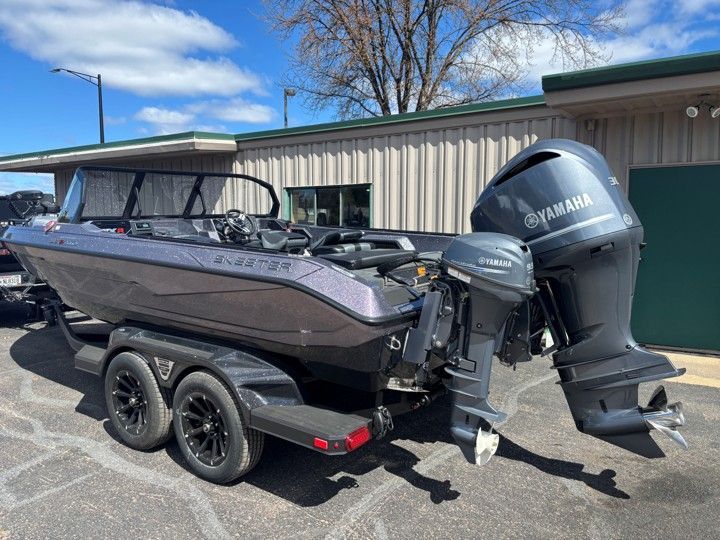 Black fishing boat on a trailer with Yamaha outboard, parked outside a building under a blue sky
