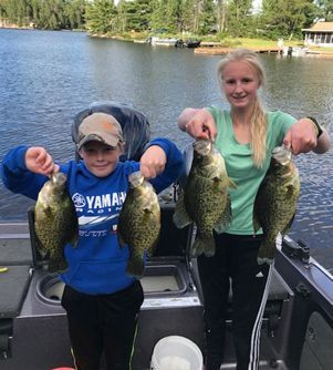 A boy and a girl are holding fish on a boat