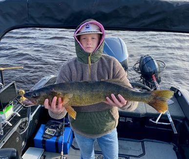A young boy is holding a large fish on a boat