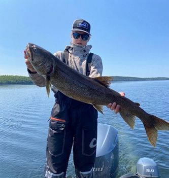 A boy is holding a large fish in front of a boat