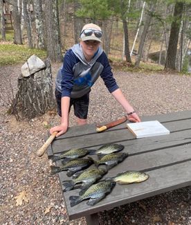 A man is standing next to a picnic table with fish on it