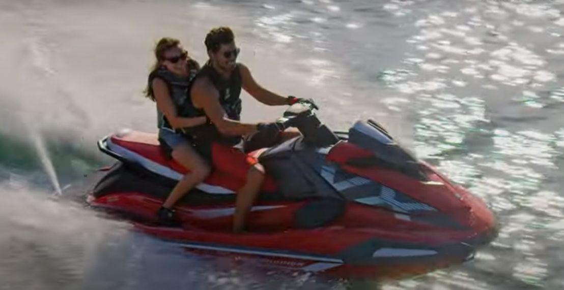 A man and a woman are riding a jet ski in the water