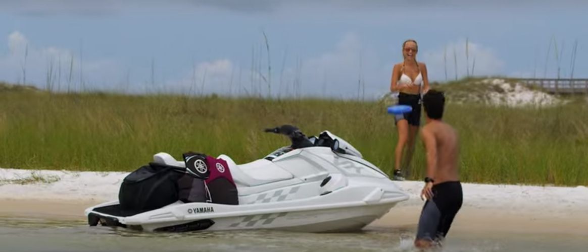 A man and a woman are standing next to a jet ski on the beach