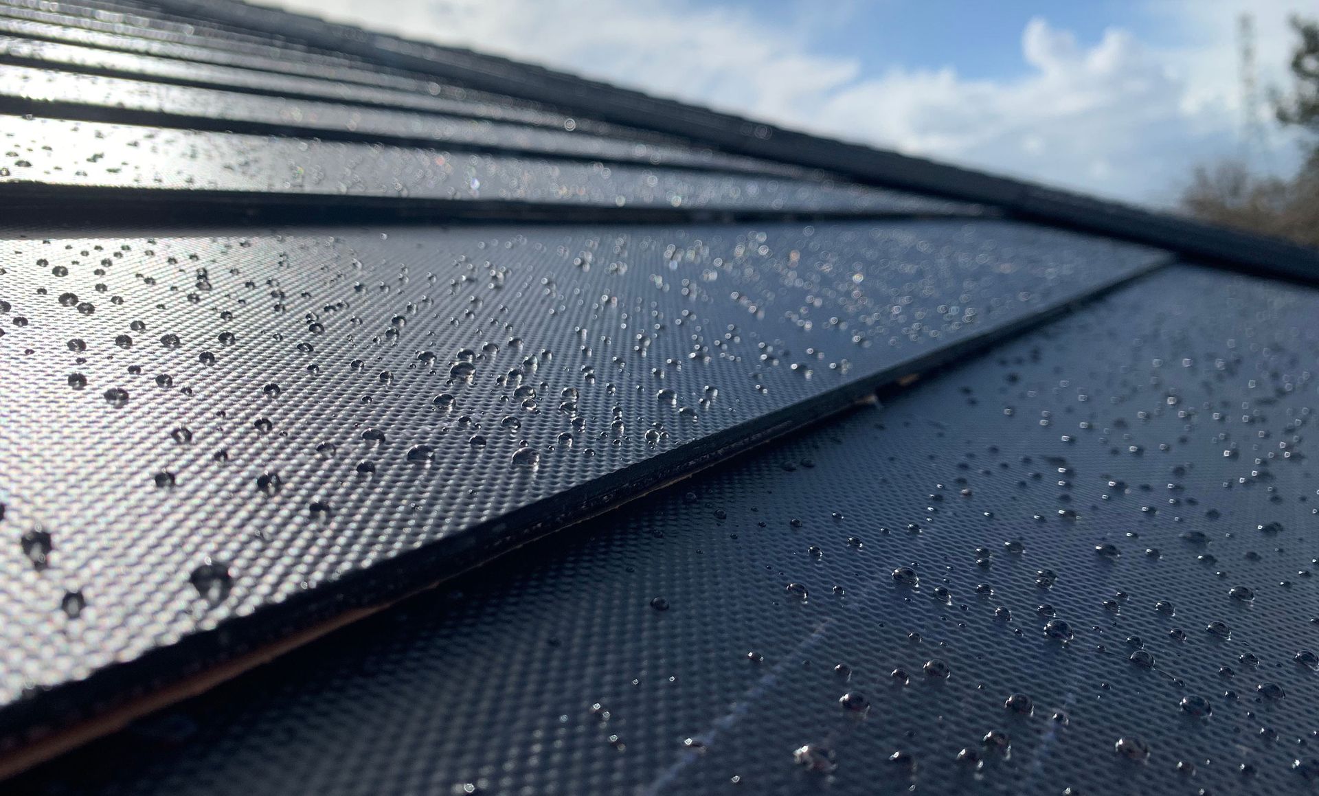 A close up of a black roof with water drops on it