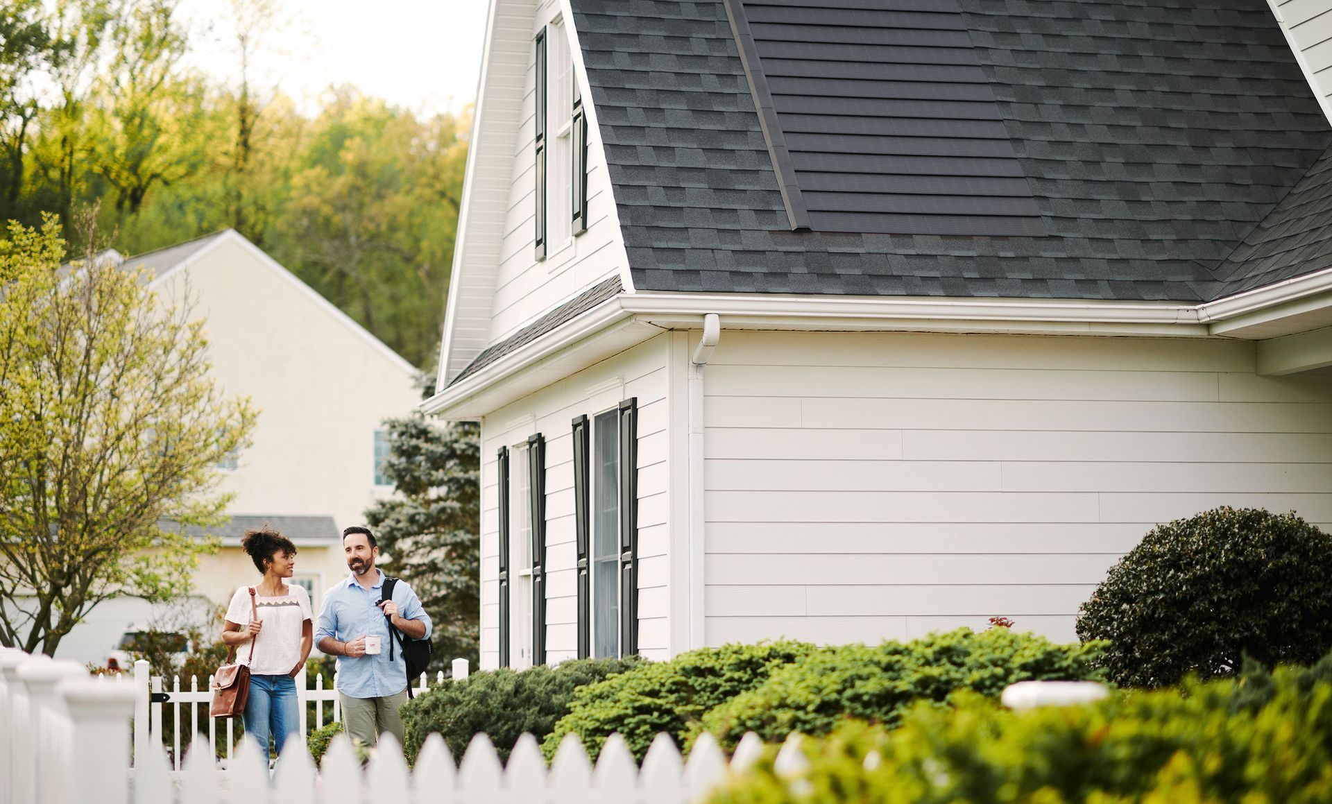 A man and woman are standing in front of a white house.