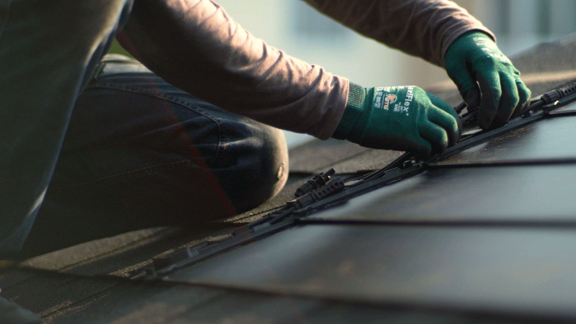 A person wearing green gloves is cleaning the windshield of a car.