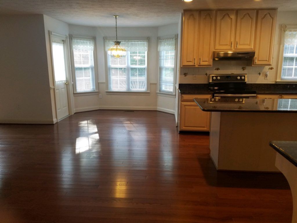 an empty kitchen with hardwood floors and white cabinets