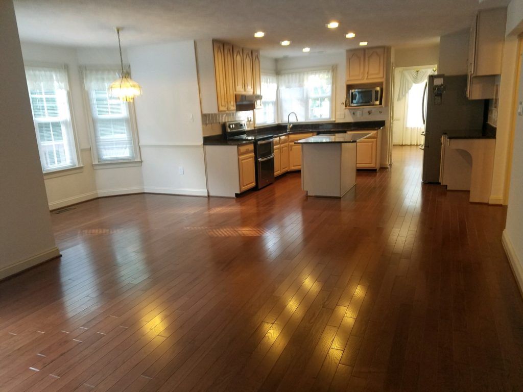 an empty kitchen with hardwood floors and white cabinets