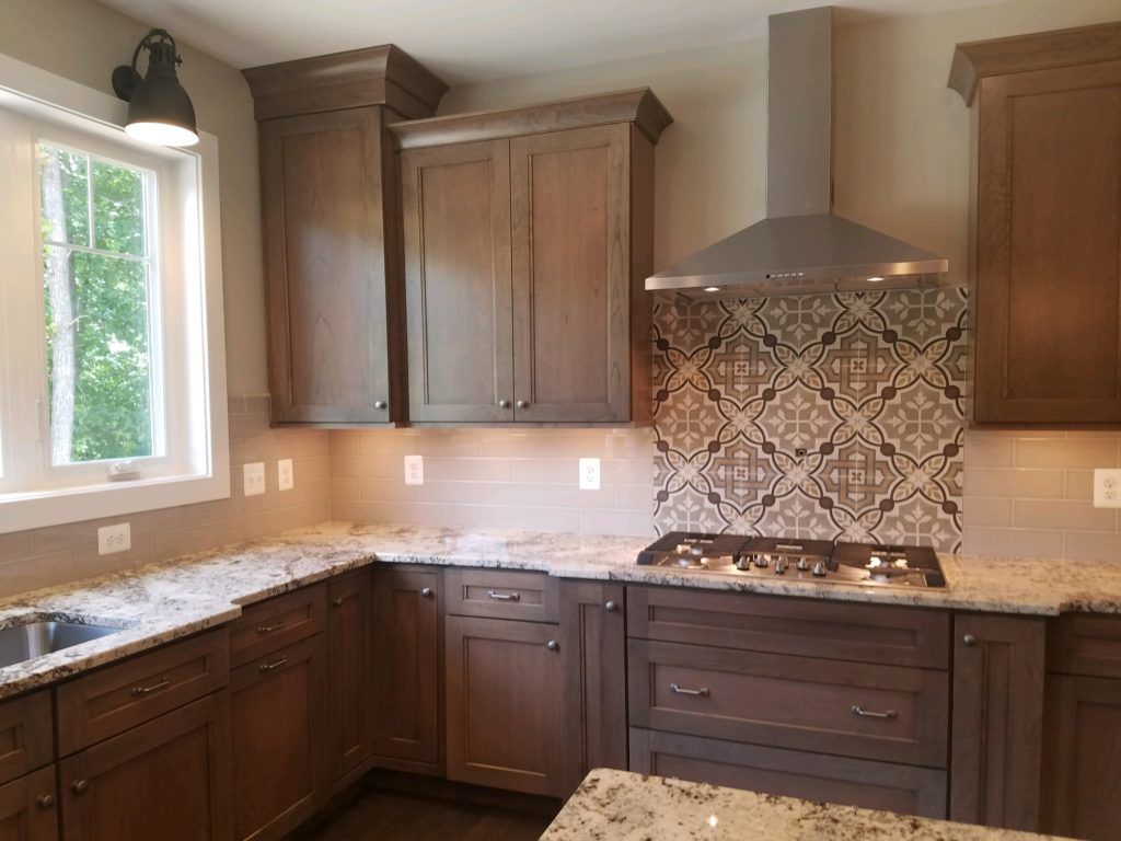 a kitchen with wooden cabinets, granite counter tops, a stove and a window