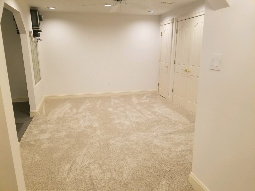 an empty basement with a carpeted floor and white walls