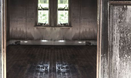 An empty room with a wooden floor and two windows