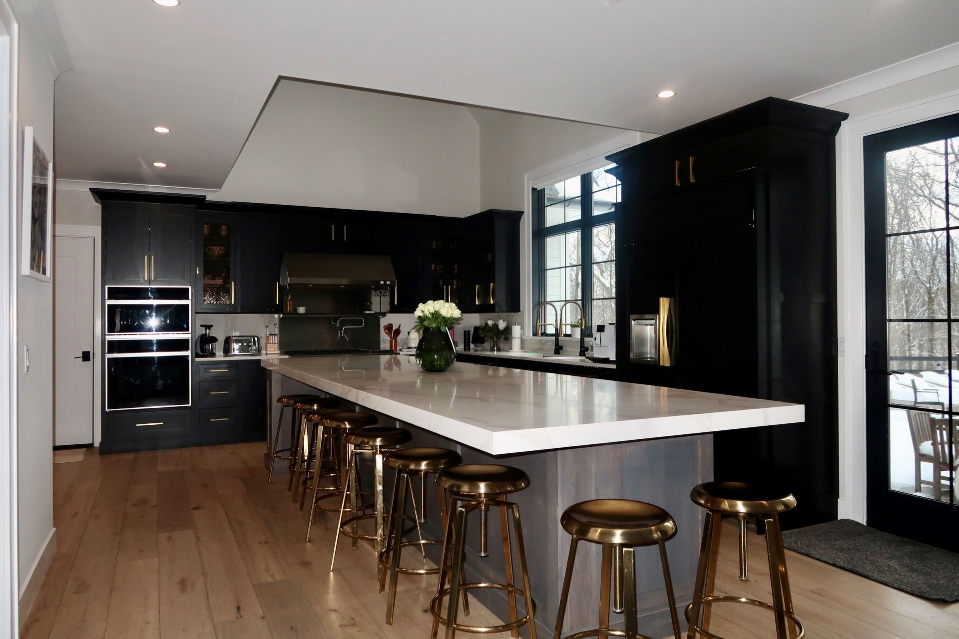 A kitchen with black cabinets and gold stools