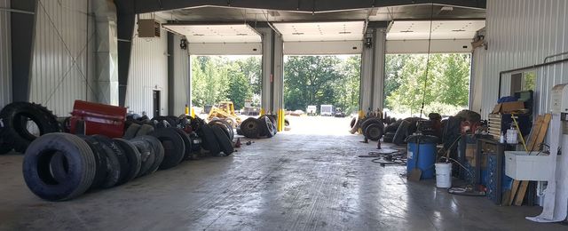 Row of off-road tires and tools inside a garage with an open view to daylight outside