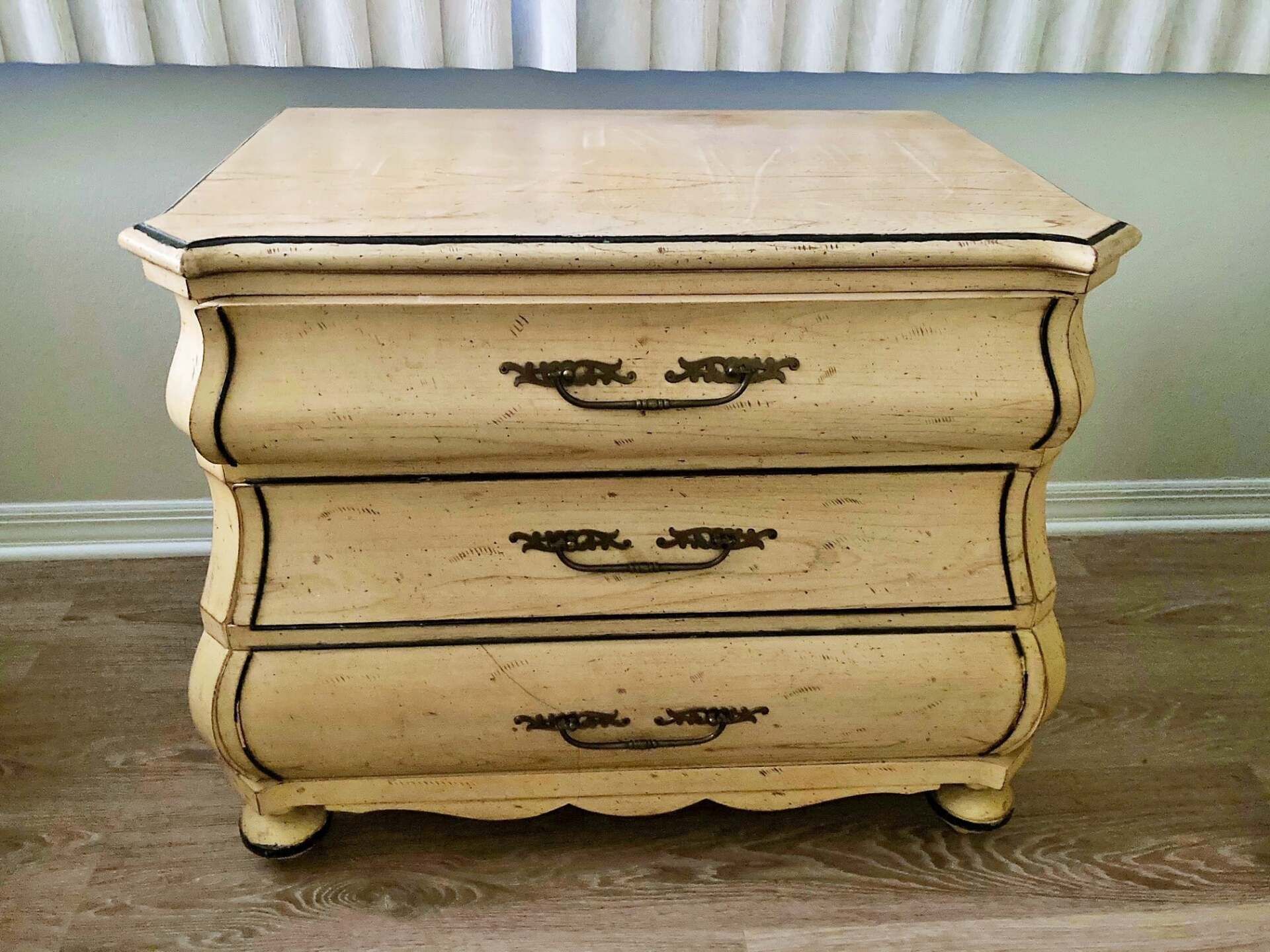 a white nightstand with three drawers is sitting on a wooden floor