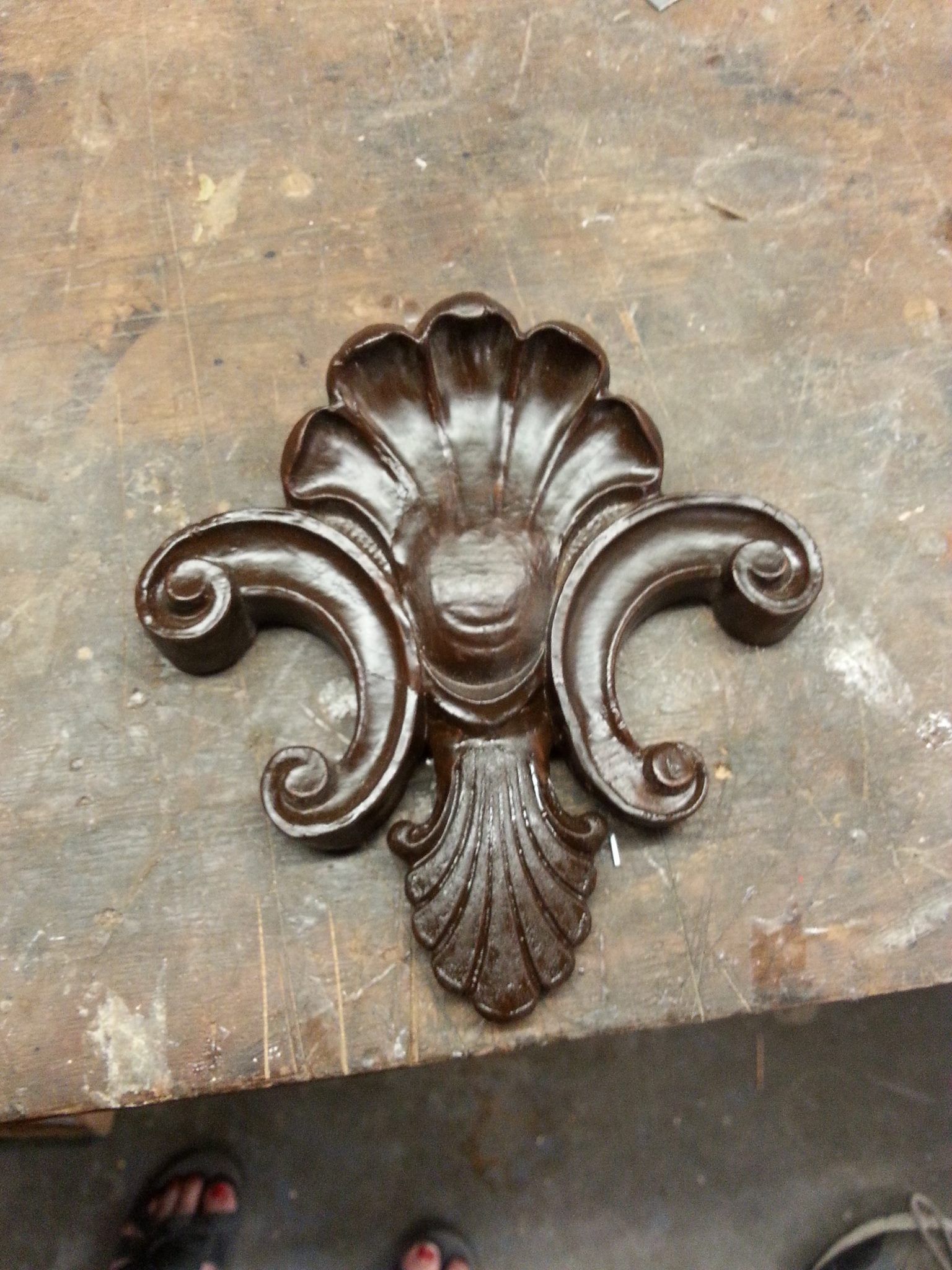a wooden carving of a flower is sitting on a wooden table