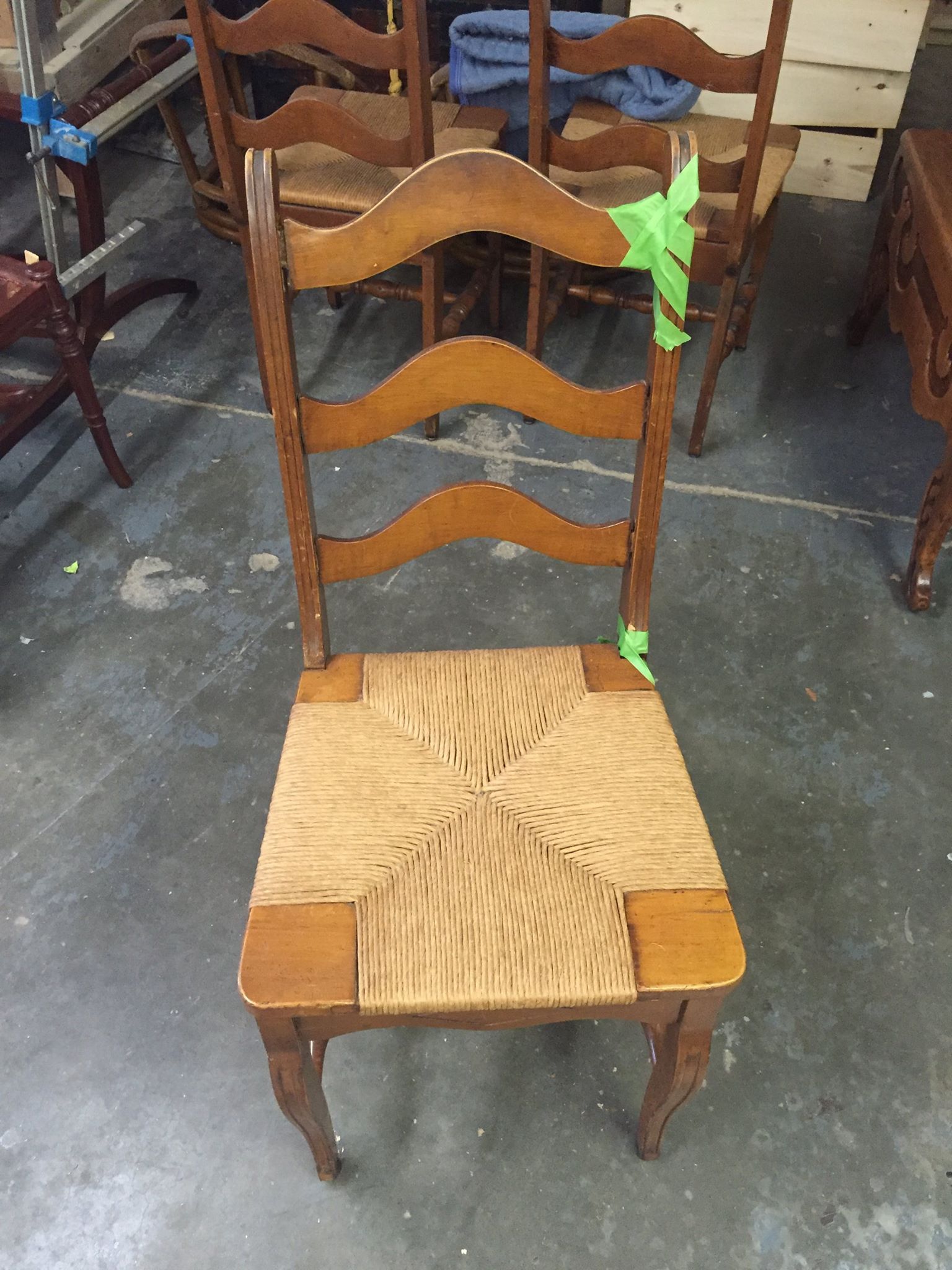 a wooden chair with a wicker seat is sitting on a concrete floor