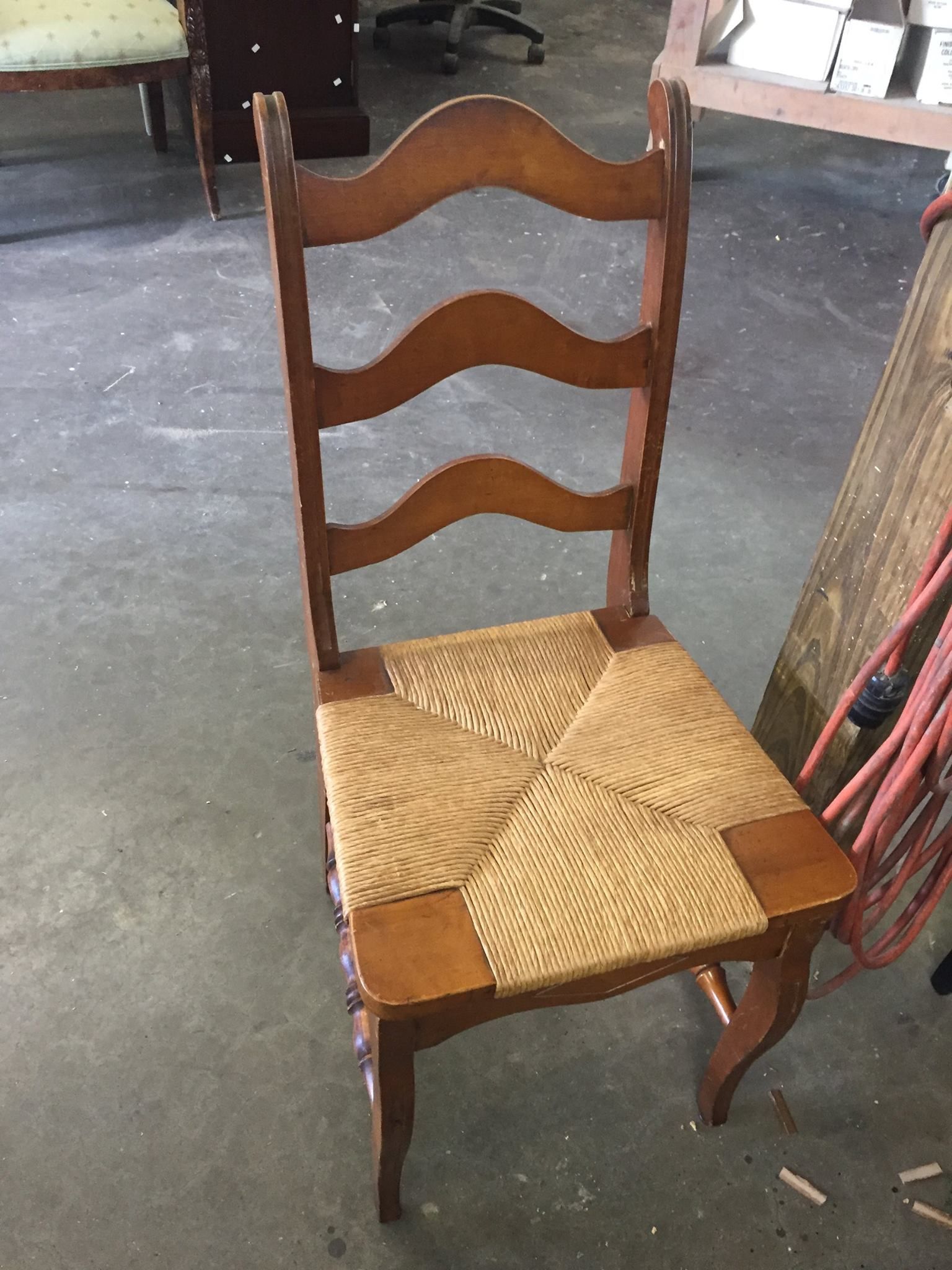 a wooden chair with a wicker seat is sitting on a concrete floor
