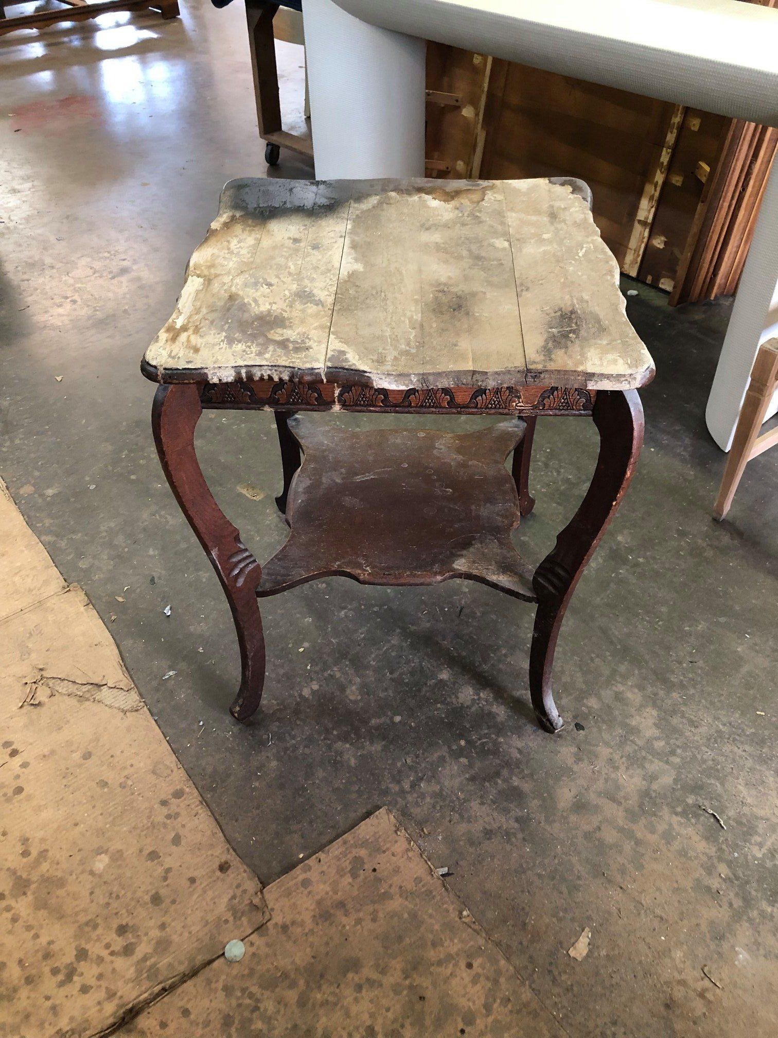 a small table with a shelf underneath it is sitting on a concrete floor