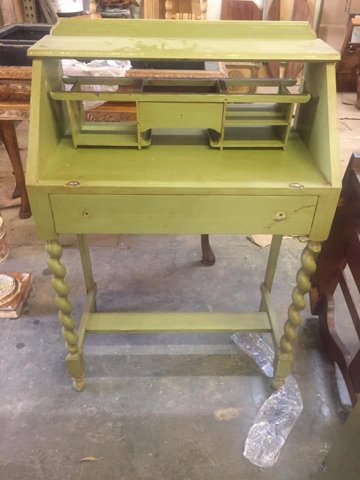 a green desk with a drawer and a shelf is sitting on the floor