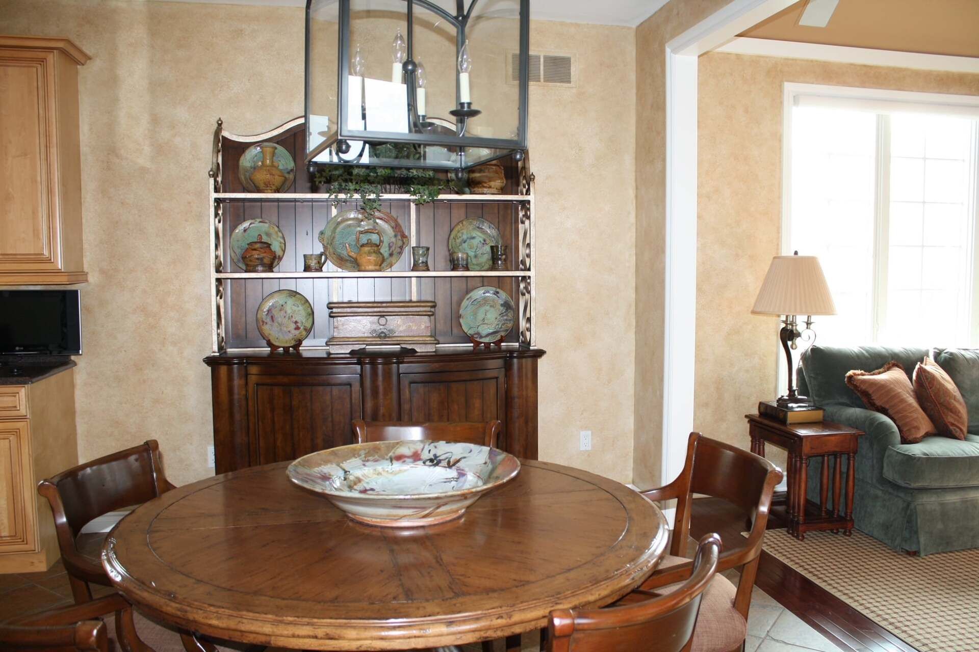 a dining room with a round table and chairs and a hutch with plates on it