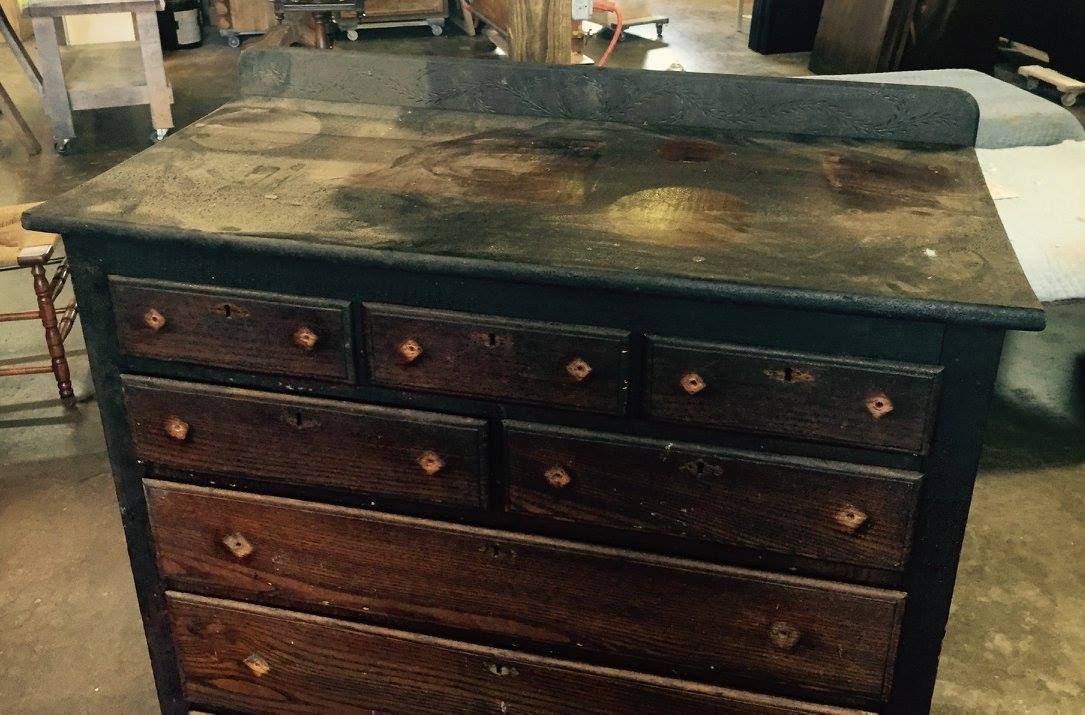 a wooden chest of drawers is sitting on a table in a room