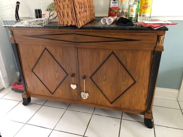 a wooden cabinet with a black top is sitting on a tiled floor