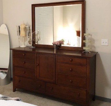 a bedroom with a dresser, mirror, and mannequin