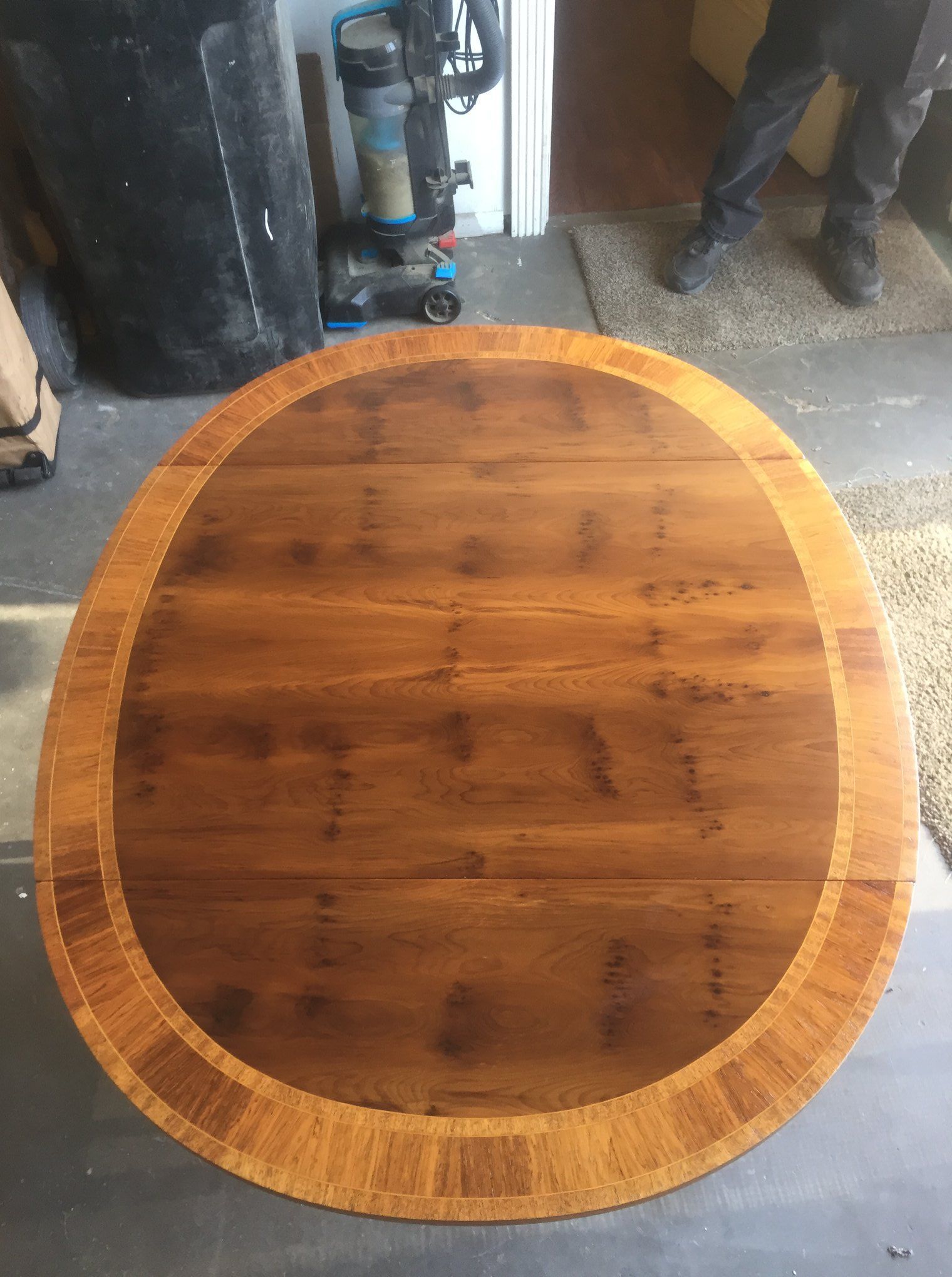 a wooden table with a round top is sitting on a concrete floor