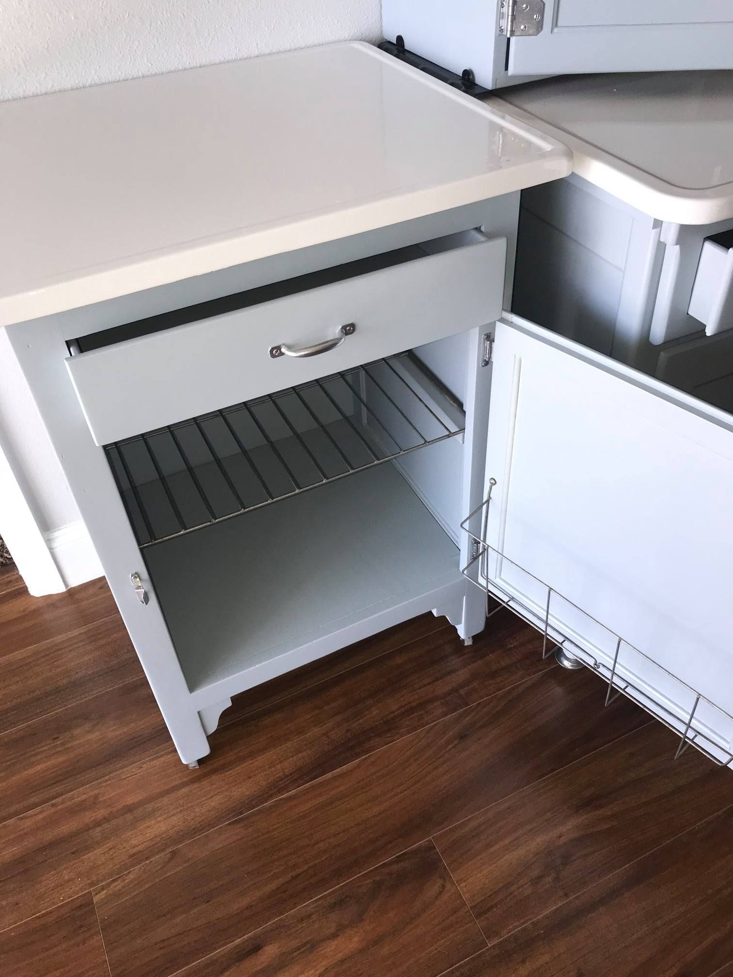 a white cabinet with a drawer and a shelf underneath it