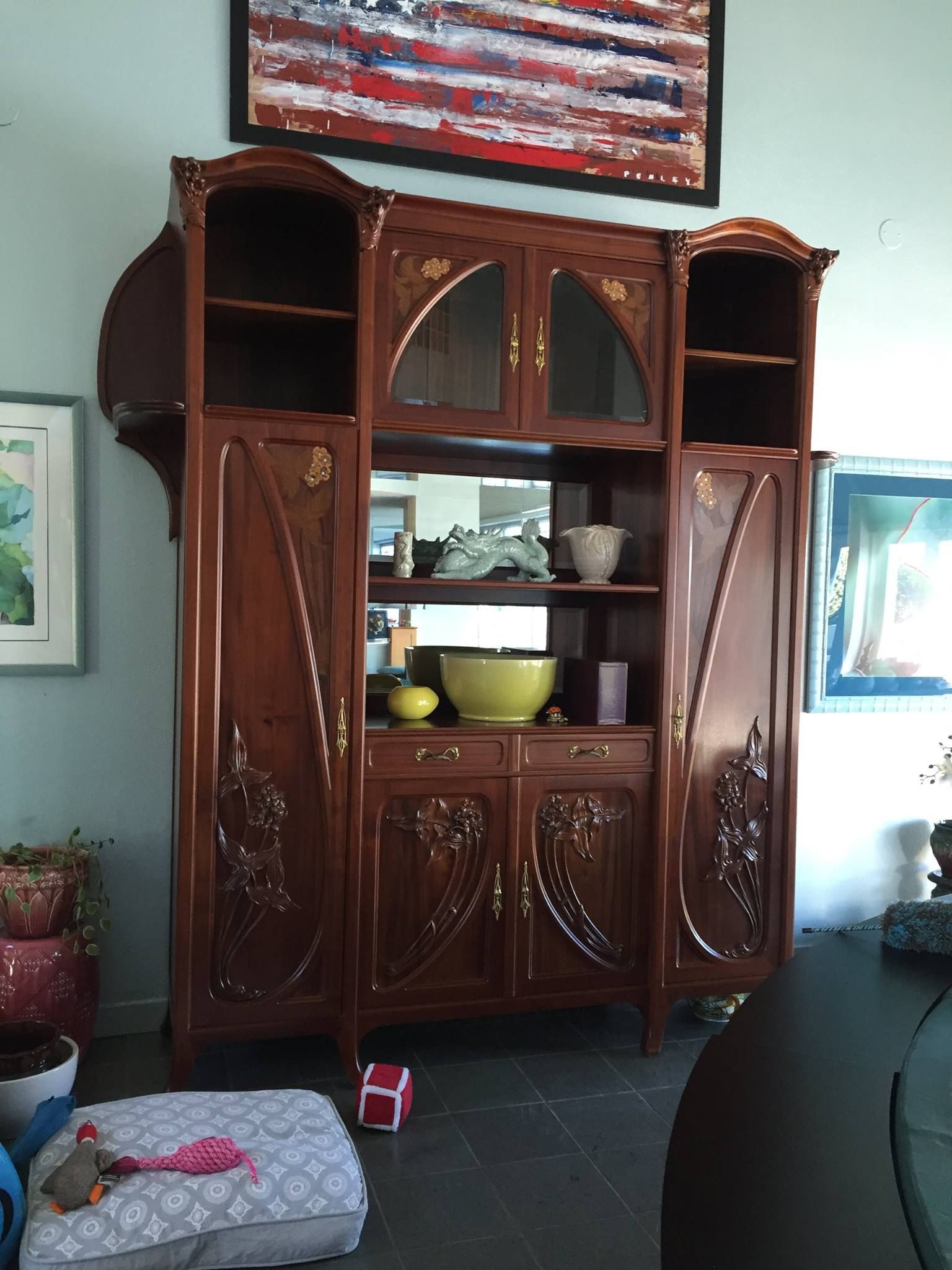 a living room with a large wooden cabinet and a painting on the wall above it