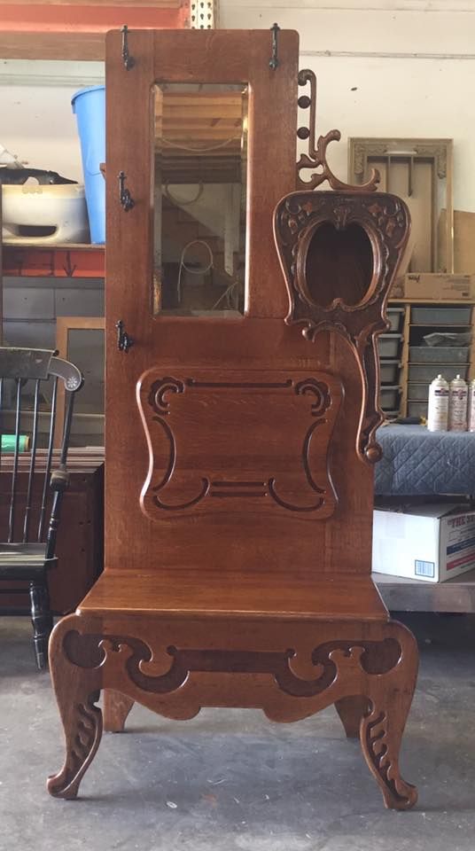 a wooden coat rack with a mirror and hooks