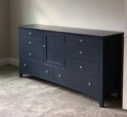 a blue dresser is sitting in a bedroom next to a door