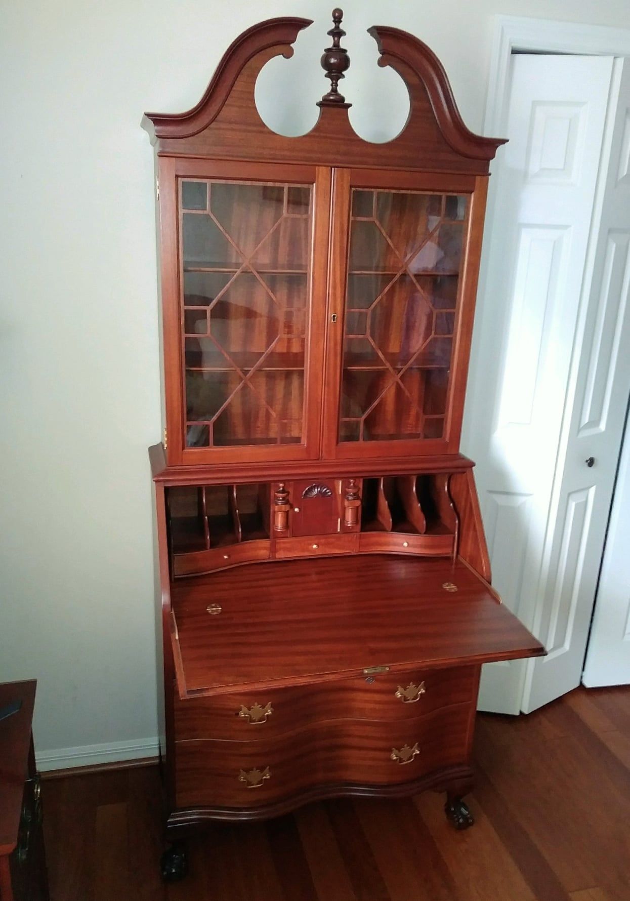 a wooden desk with a glass hutch on top of it in a room
