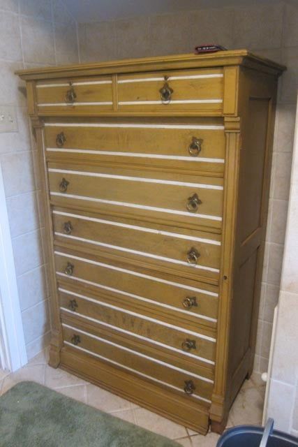 a wooden chest of drawers is sitting in a bathroom next to a green rug