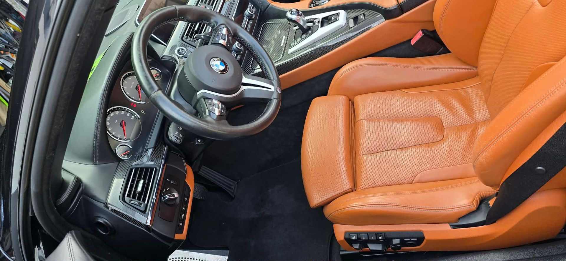 Orange leather car interior with steering wheel, dashboard, and front seats viewed from the driver’s side