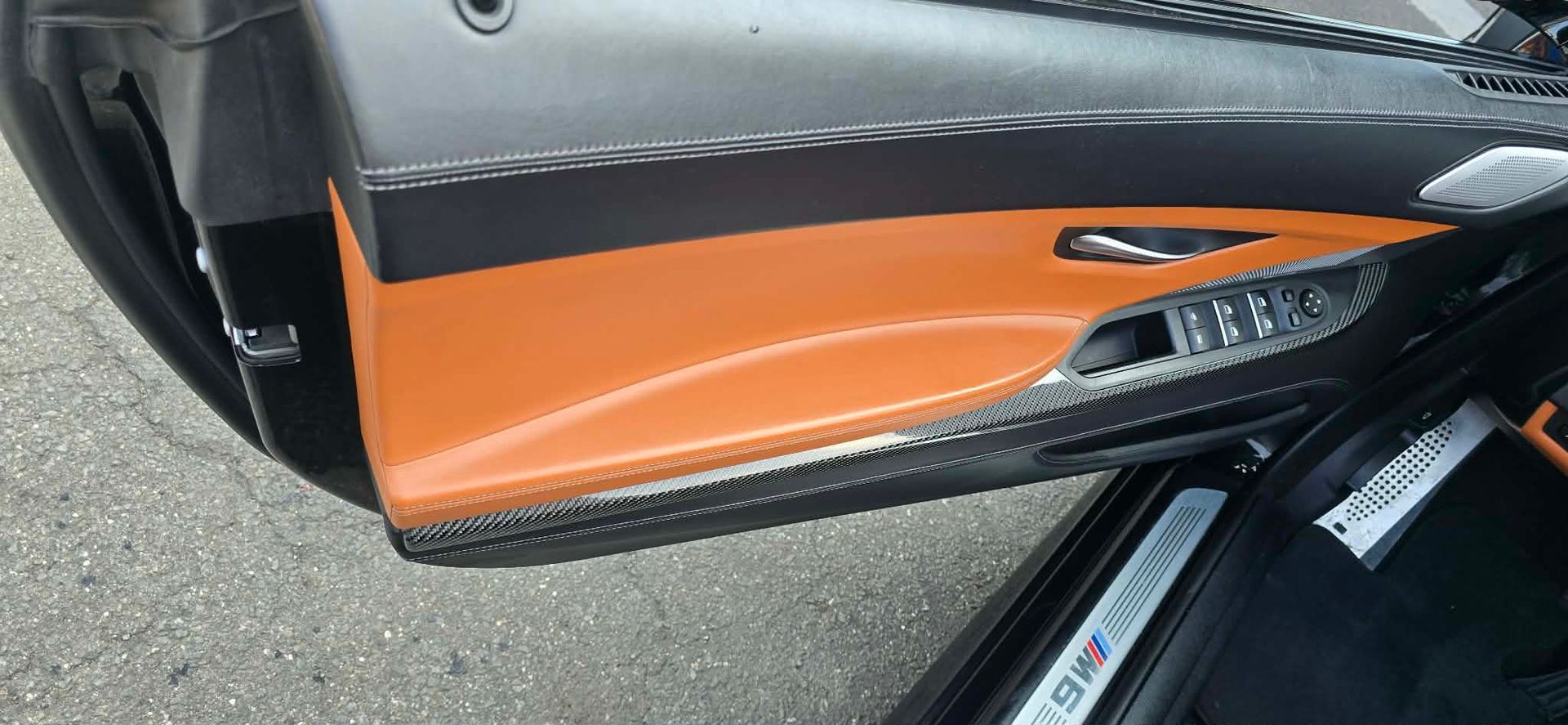 Close-up of a black and orange sports car door with a glossy side vent