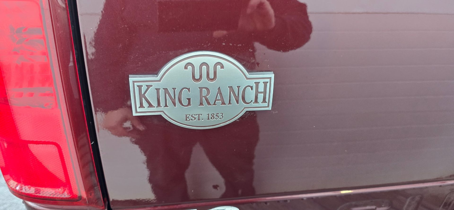Close-up of a maroon car trunk with a King Ranch badge and left taillight.