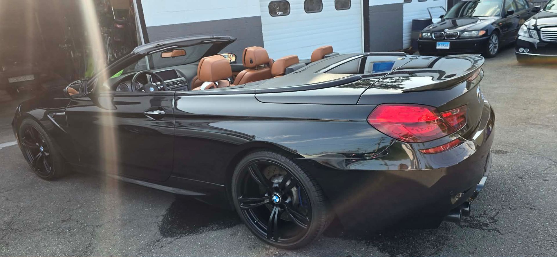 Black convertible with tan seats parked in front of a building, top down