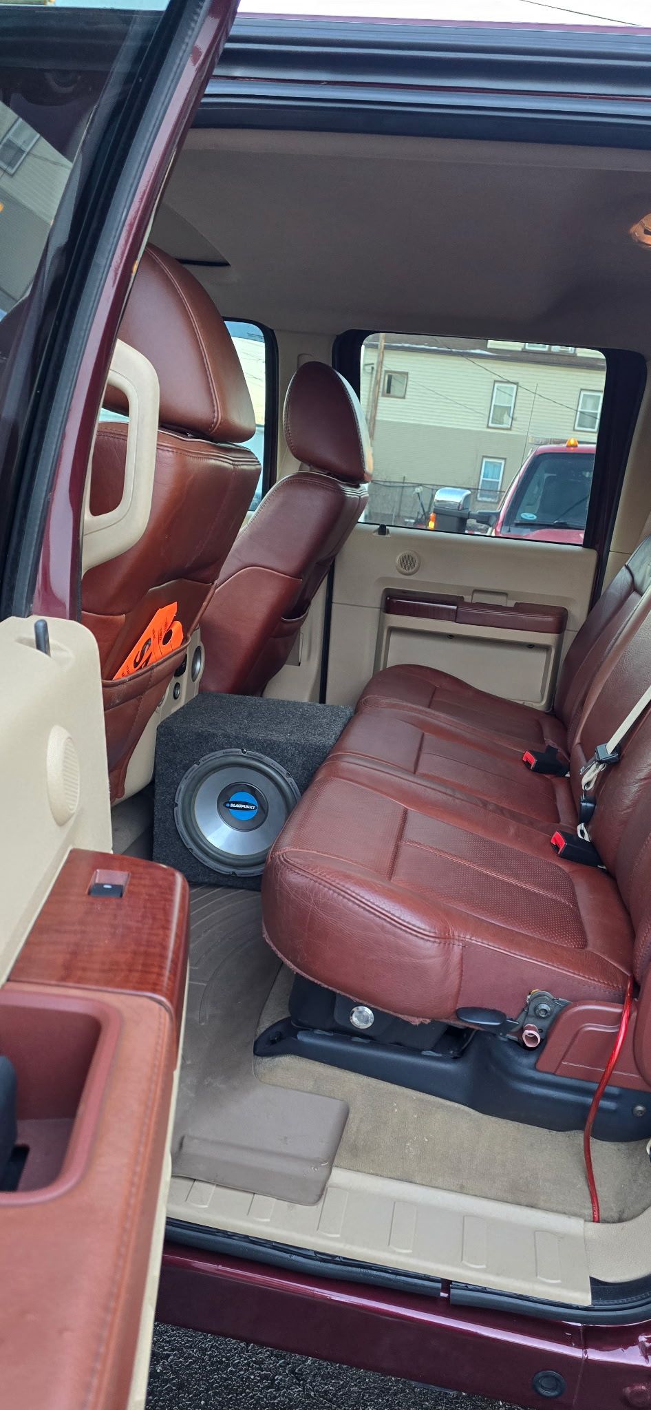 SUV interior with burgundy seats and a small blue fan on the floor, viewed from an open door