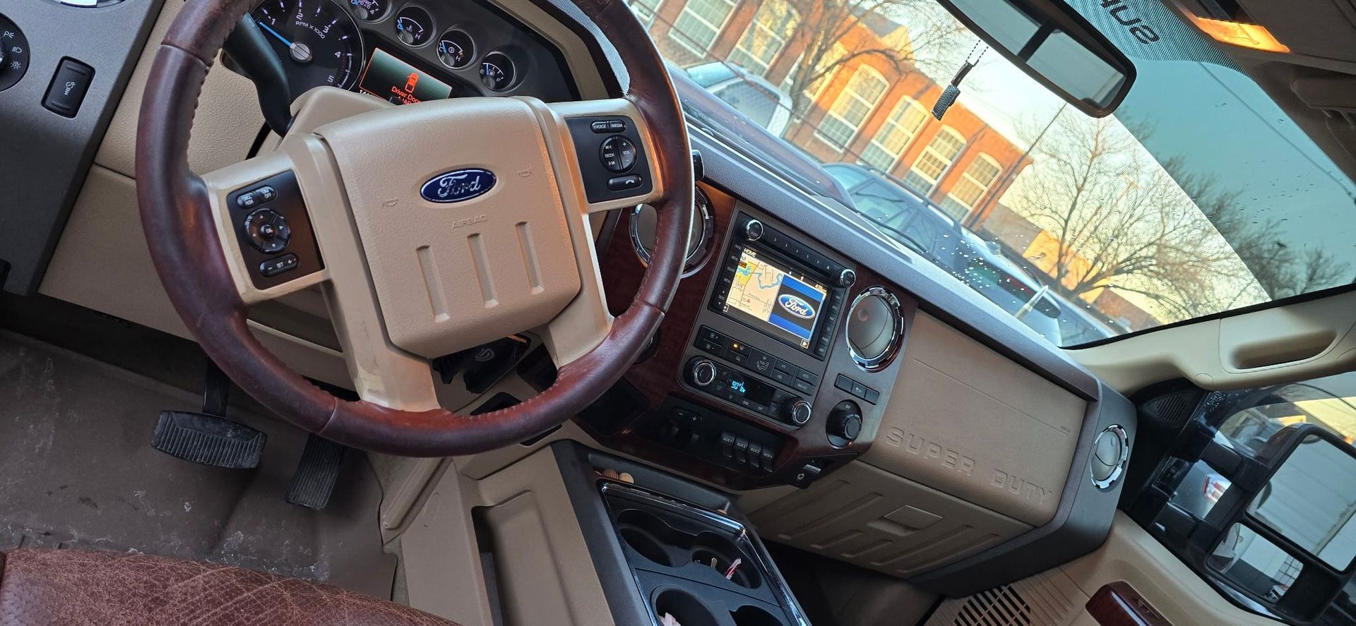 Ford truck interior with tan steering wheel, dashboard, and center console in daylight