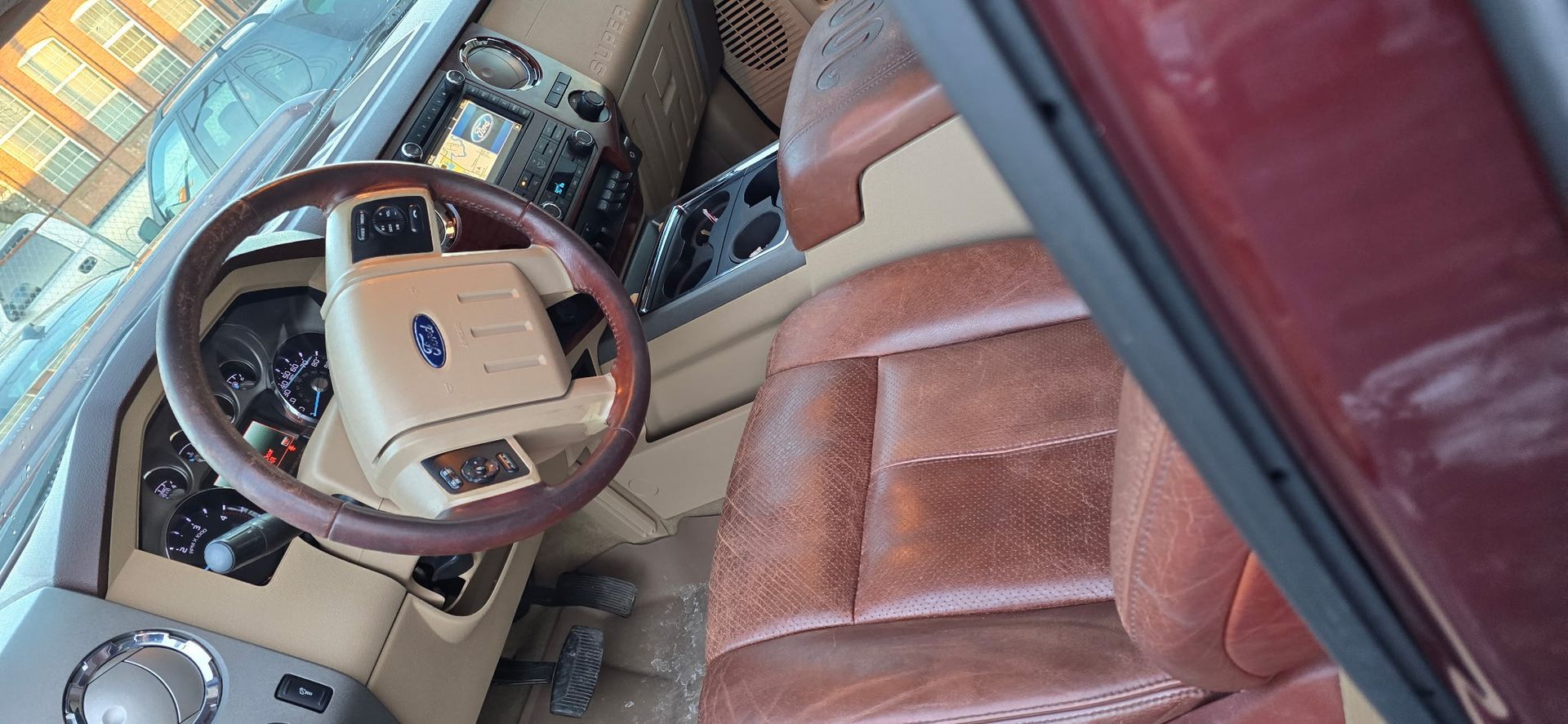 Interior of a beige car with tan seats, steering wheel, and dashboard visible from the open door.