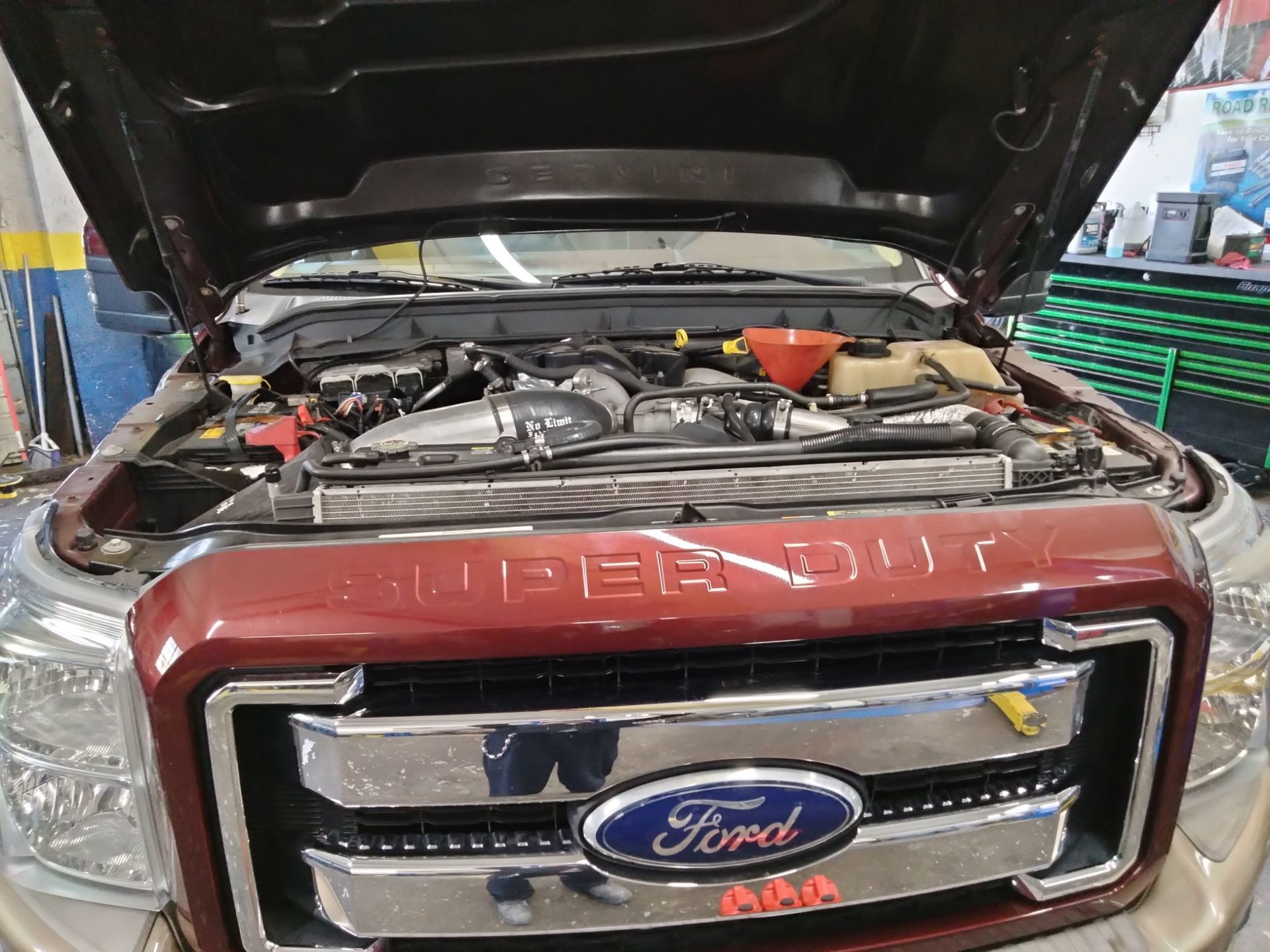 Open Ford truck hood showing engine compartment and front grille with logo