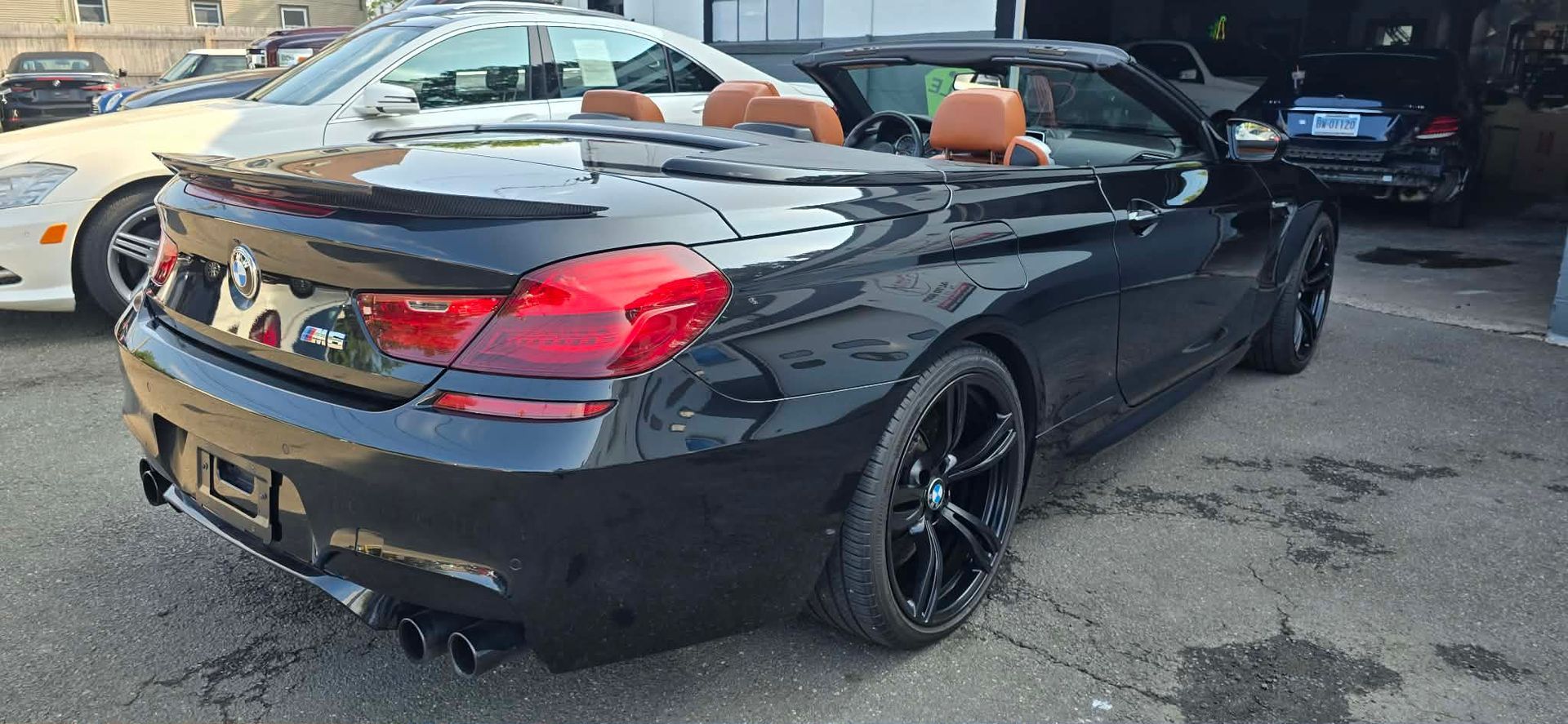 Black convertible sports car with orange interior parked in a garage.
