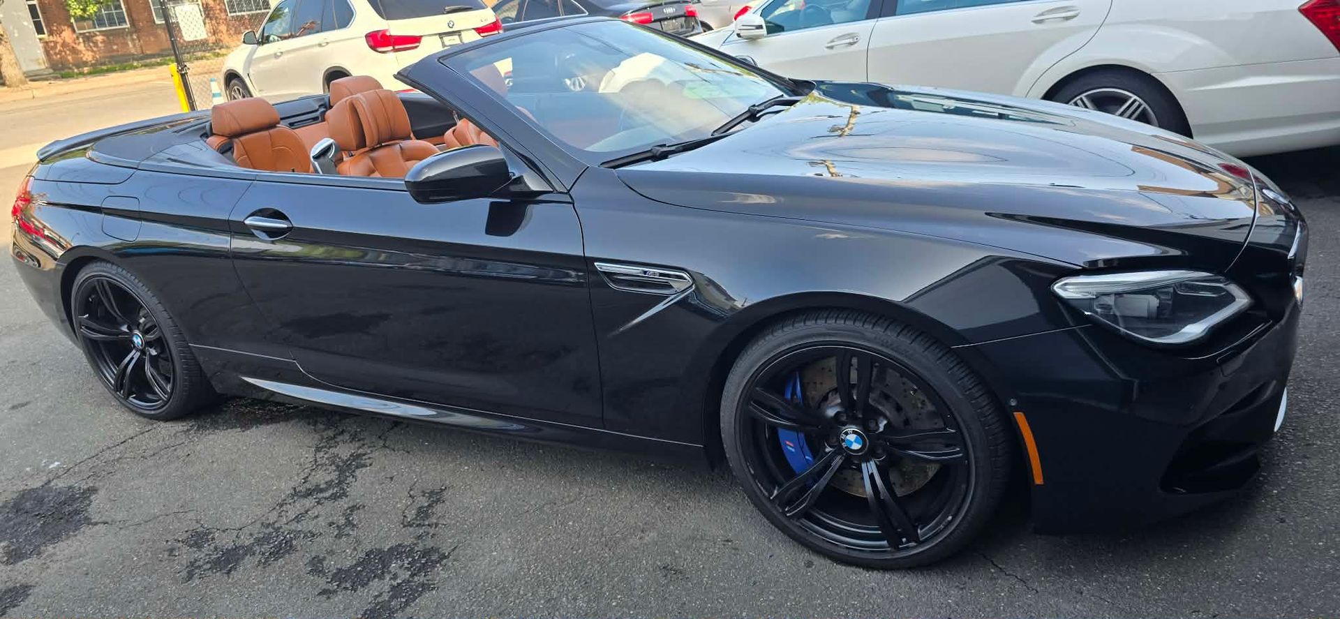 Black convertible sports car with tan interior parked on a city street