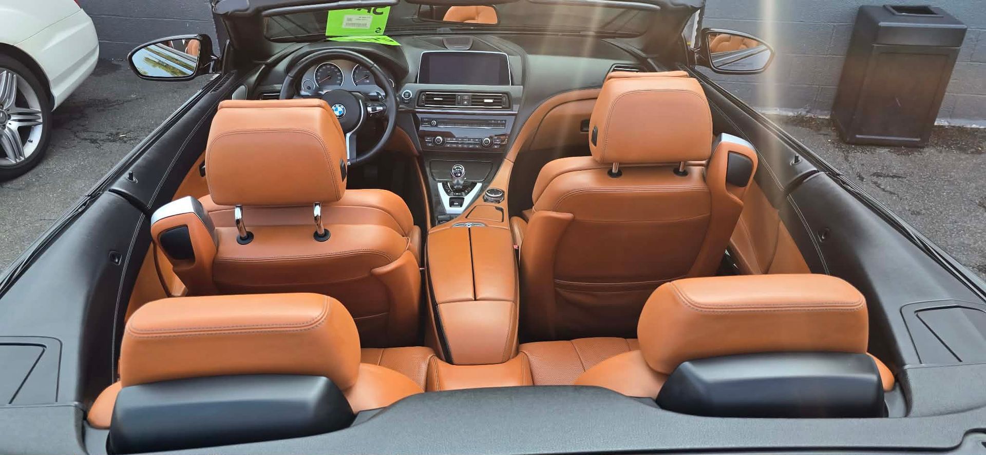 Luxury convertible interior with tan leather seats and black dashboard, viewed from the back seat