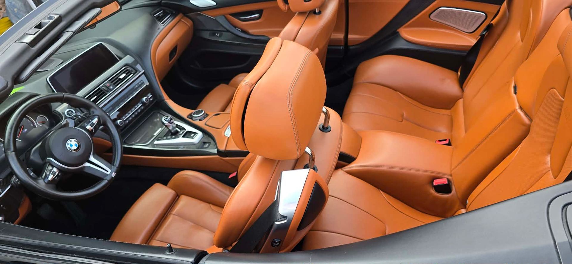 Orange leather sports car interior with black dashboard and steering wheel, viewed from above