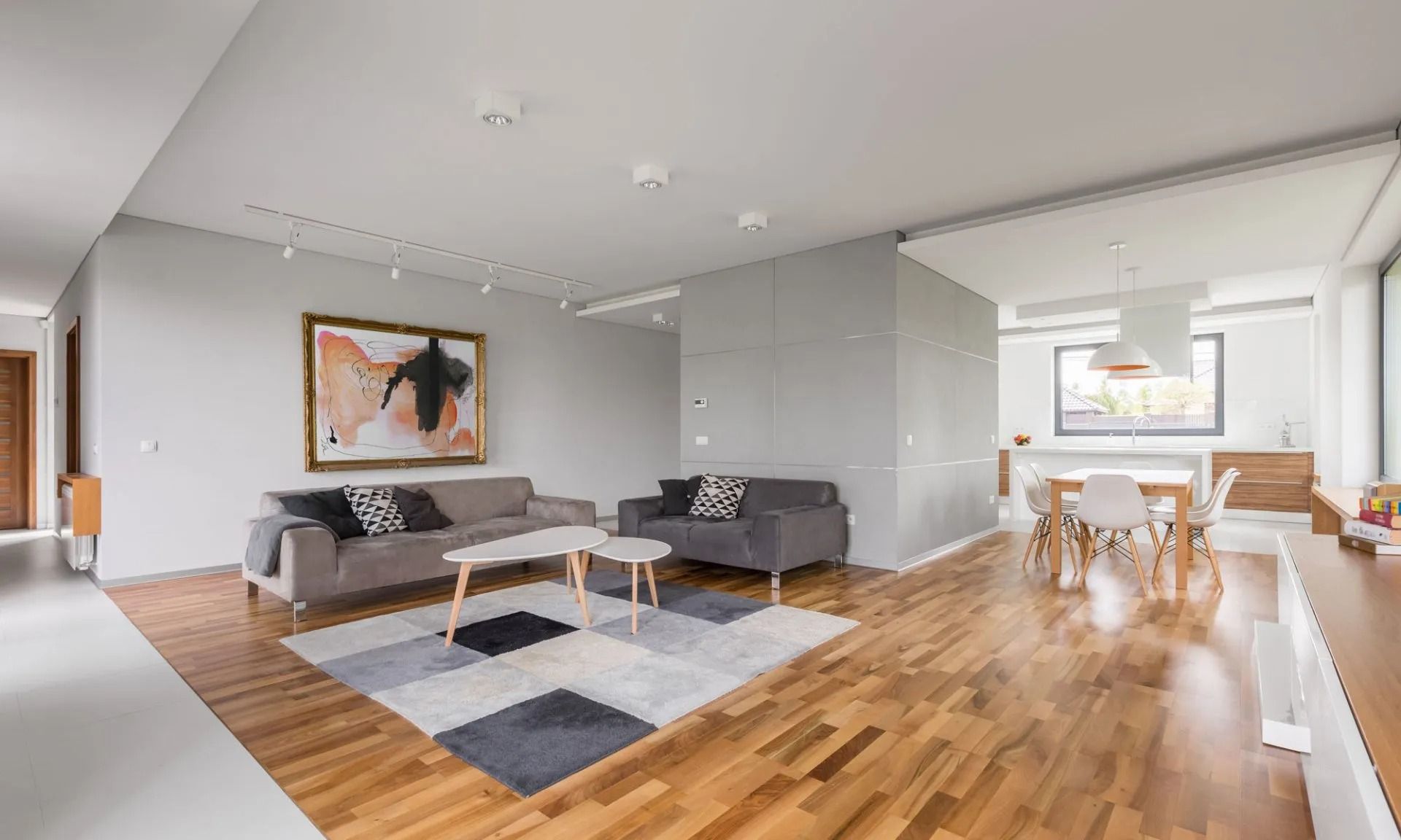 Spacious modern living room with gray walls, wooden floor, and a colorful rug.