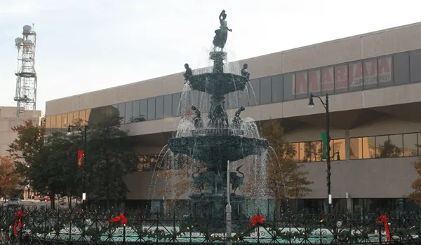 Fountain in front of a tan building with glass windows; water flows.