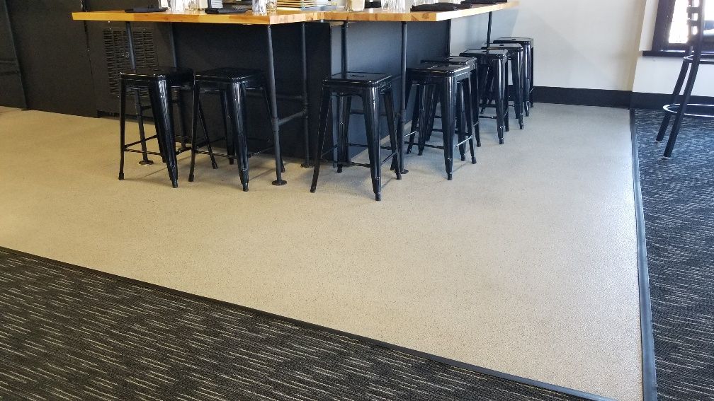 A room with a bar and stools on the floor.
