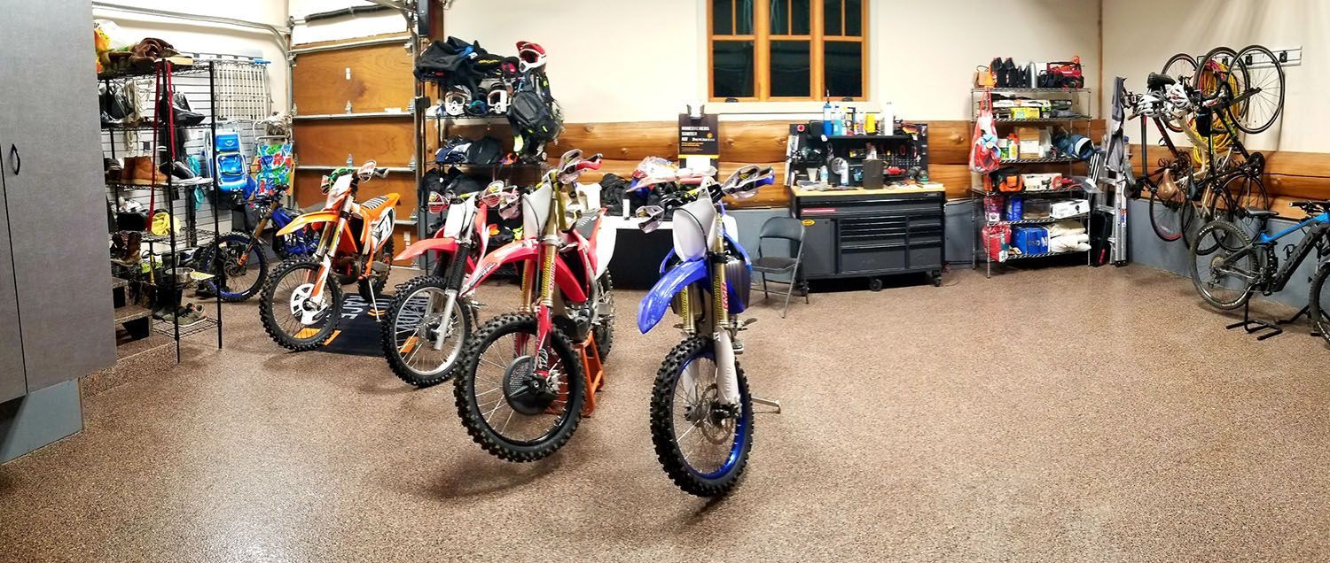 A row of dirt bikes are parked in a garage.